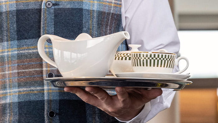 A waiter carrying a tray of tea on Spirit of Adventure